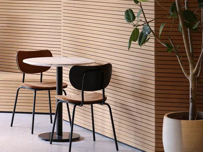 Cozy dining area with wooden paneling, two chairs, and a small table, lit by three lights
