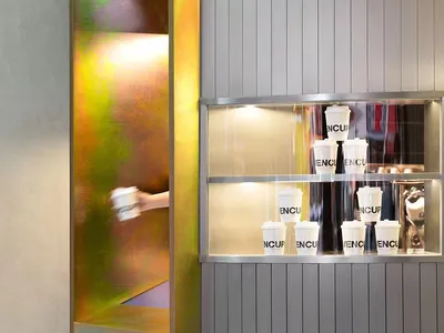 A clean and organized interior space with a large mirror, several cups, and white surfaces
