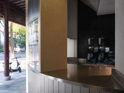 A casual coffee shop interior with a counter, refrigerator, and multiple cups on surfaces, featuring customers enjoying their time in a welcoming atmosphere