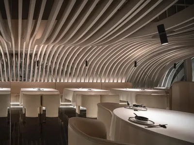 A modern restaurant interior with white tables and chairs arranged in rows, creating a spacious and inviting atmosphere with clean lines and minimalistic elements