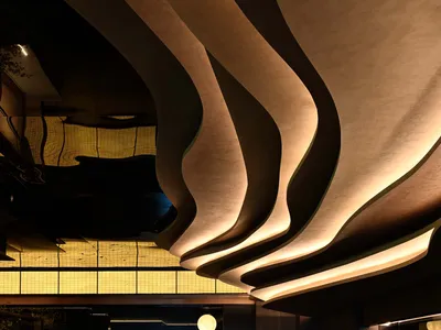 Elegant hotel lobby with a curved wooden wall, bottles, and two chairs, featuring a sophisticated atmosphere and attention to both aesthetics and functionality