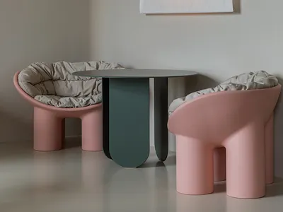 A modern dining space with two pink chairs and a couch, well-lit with natural or artificial light, creating a cozy atmosphere