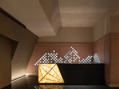 Modern hotel lobby with a diamond-shaped black countertop desk, two chairs, and a sophisticated ambiance