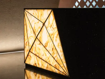 A luxurious hotel lobby interior featuring a black marble countertop with a yellow and brown pattern, two triangular shapes, and a sophisticated atmosphere