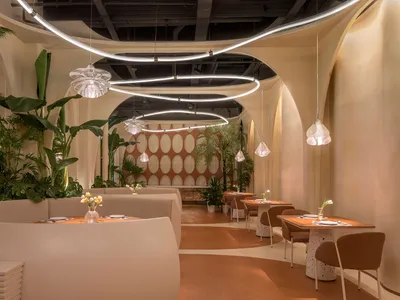 Modern restaurant interior with white walls, brown floors, and dining tables and chairs
