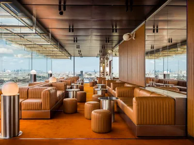 Warm and inviting restaurant interior with orange carpeting, couches, chairs, and dining tables