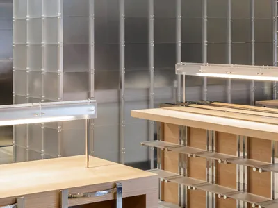 Modern kitchen with wooden cabinets, stainless steel countertops, and ample lighting from two overhead lights