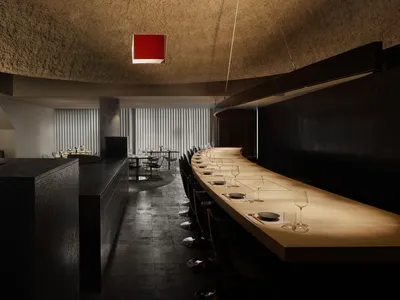 現代餐廳內部，長形木質餐桌環繞黑色座椅、酒杯與高級氛圍