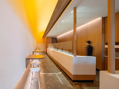 A casual restaurant interior with a wooden counter and three chairs, creating a warm and inviting atmosphere for customers to enjoy their meals