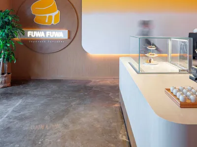 溫馨咖啡廳內部，展示櫃陳列著蛋糕與甜甜圈，櫃檯上擺放著杯子