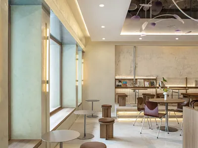 A modern restaurant dining area with tables, chairs, potted plants, artwork on the walls, and a welcoming atmosphere