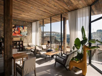 A bright and inviting living space with a large window, chairs, a dining table, and potted plants