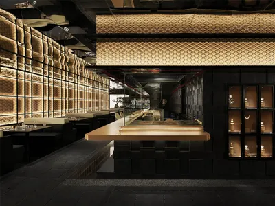A modern restaurant bar with a glass display case and bottles on the countertop, set in a sophisticated atmosphere