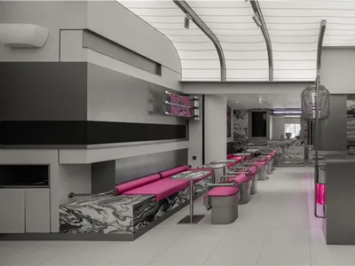 A modern restaurant interior with pink accents, artwork on the walls, and ample seating for guests