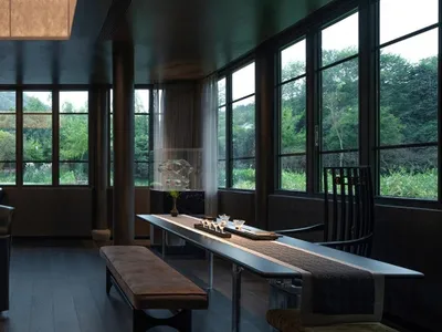 A modern dining area with a black table and chairs, surrounded by wine glasses, and natural light from windows