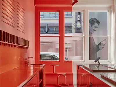 Warm kitchen with red walls, natural light, and a chair for dining or additional seating