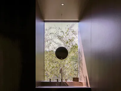 A well-lit bathroom with two sinks, one with a mirror above, under a window, with a clean and organized atmosphere