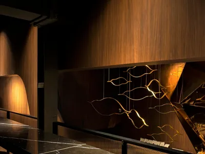 A well-lit piano bar with a black marble countertop, modern design, and a large mirror above, surrounded by chairs and a dining table
