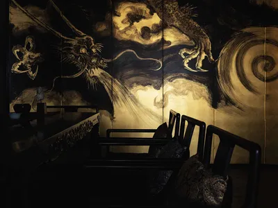 溫馨亞洲餐廳內部，木質餐桌環繞座椅與黑色座椅，營造親密用餐體驗