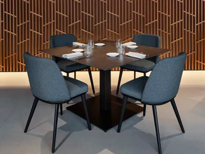 Cozy dining space with a wooden table and grey chairs, surrounded by cups and a warm atmosphere