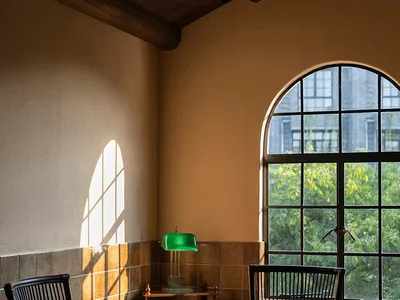Cozy room with a wooden ceiling, stone wall, two chairs, a dining table, and a clock on the wall