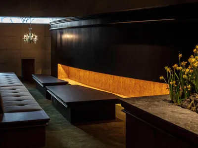 Cozy living space with two wooden benches and three potted plants, surrounded by a wooden wall