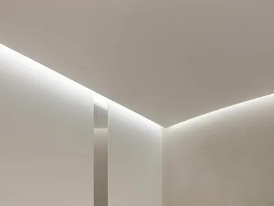燈光柔和的餐廳內部，擁有白色牆面與地板，以及各式椅子，營造出乾淨現代的氛圍