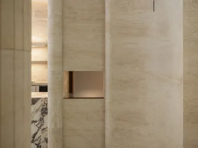 Empty hotel hallway with marble walls, a light fixture, and a calm atmosphere