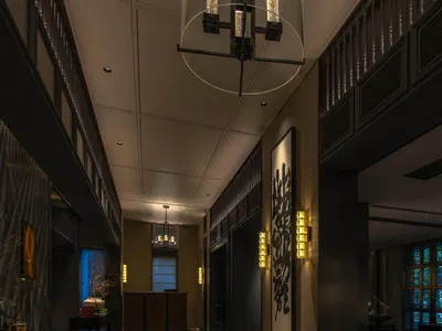A hotel lobby with a checkered tile floor, a large chandelier, potted plants, and decorative vases create a stylish and inviting atmosphere
