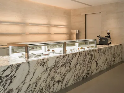 大理石麵檯烘焙櫃檯，陳列各式蛋糕與杯具，置於溫馨的餐廳環境中