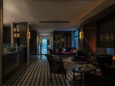 A modern and sophisticated hotel lobby with a black and white checkered floor, featuring various pieces of furniture and decorative bottles