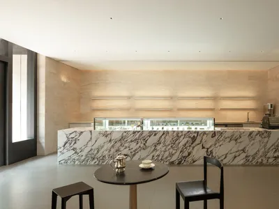 A restaurant dining area with a marble countertop, a dining table, and two chairs, featuring a bowl on the table and a luxurious ambiance
