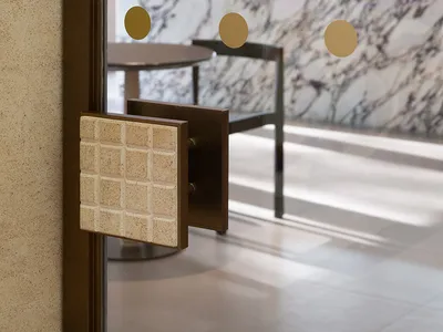 Elegant dining space with a marble wall, a brown door handle, and a dining table between two chairs