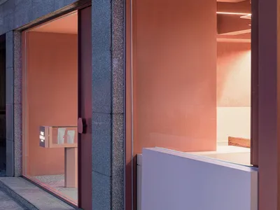 A restaurant interior with pink walls, concrete surfaces, and abundant natural light from large windows