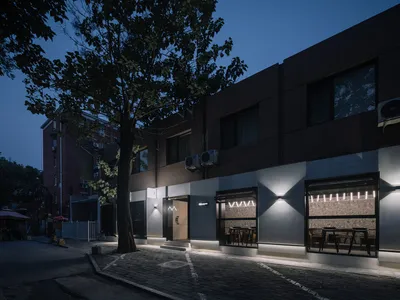 夜晚棕色外觀的餐廳，餐桌與椅凳營造出溫馨舒適的用餐氛圍