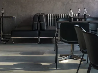 Modern restaurant interior with black leather chairs and tables, comfortable seating area, and additional seating options