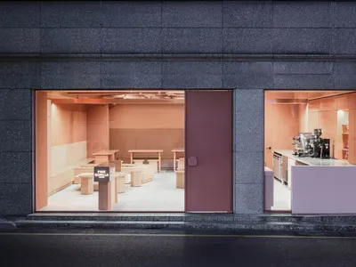 A restaurant dining area with multiple tables and chairs, pink and grey walls, and tile flooring, creating a warm and inviting atmosphere
