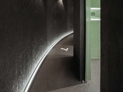 A modern hotel hallway with a black and white color scheme, featuring a green door, two clocks on the wall, and a clean and well-maintained atmosphere