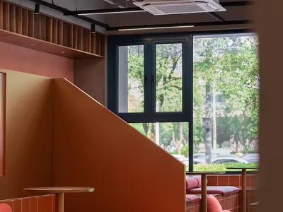 Warm and inviting dining area with orange walls, multiple chairs and tables, and a couch for added seating