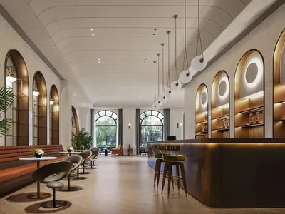 燈光明亮的飯店大廳，高挑天花板、座椅、餐桌與盆栽植物，營造溫馨氛圍