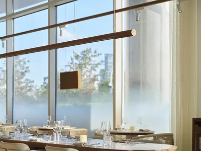 Sophisticated restaurant interior with wooden floors, white chairs, and dining tables with wine glasses