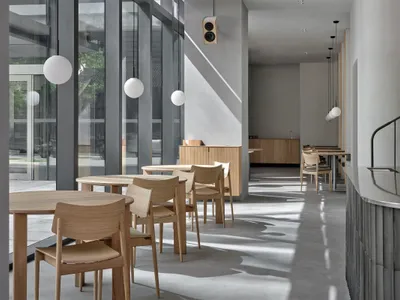 Bright modern restaurant interior with large windows, dining tables, and chairs in a clean and inviting atmosphere