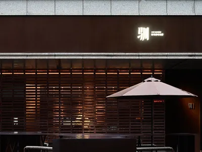 Cozy Asian restaurant with wooden walls and tables, comfortable seating, and an umbrella providing shade