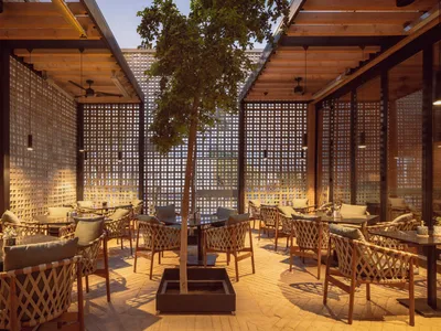 Modern restaurant interior with tile walls, potted plants, and warm lighting, featuring a dining area with tables and chairs