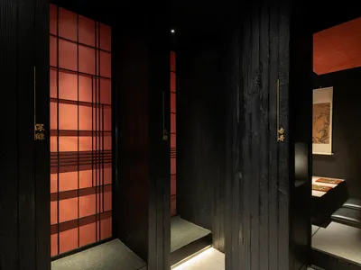亞洲風格浴室中，黑木門搭配金屬點綴與紅色磚牆