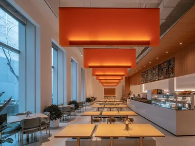 A spacious restaurant dining area with multiple tables, chairs, and potted plants, creating a warm and inviting atmosphere