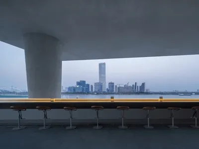 Modern restaurant bar with stools and chairs, overlooking a city skyline, with warm and inviting lighting