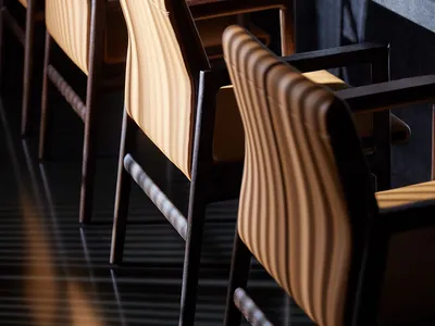 Darkened dining area with several wooden chairs arranged around a table, creating an intimate atmosphere