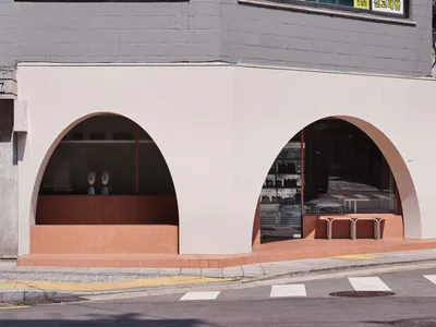 A modern building with concrete arches and a dining area with chairs and bottles, conveying a contemporary and inviting atmosphere