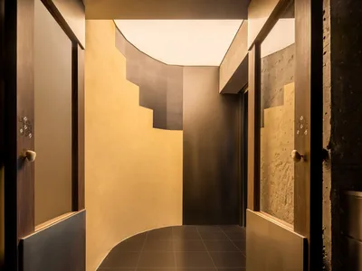 A modern hotel hallway with marble flooring, gold accents, and warm lighting